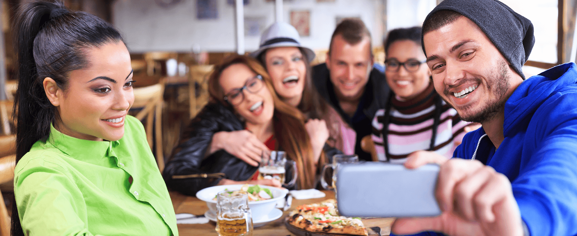 Group of friends taking selfies at a restaurant to post on Snapchat.