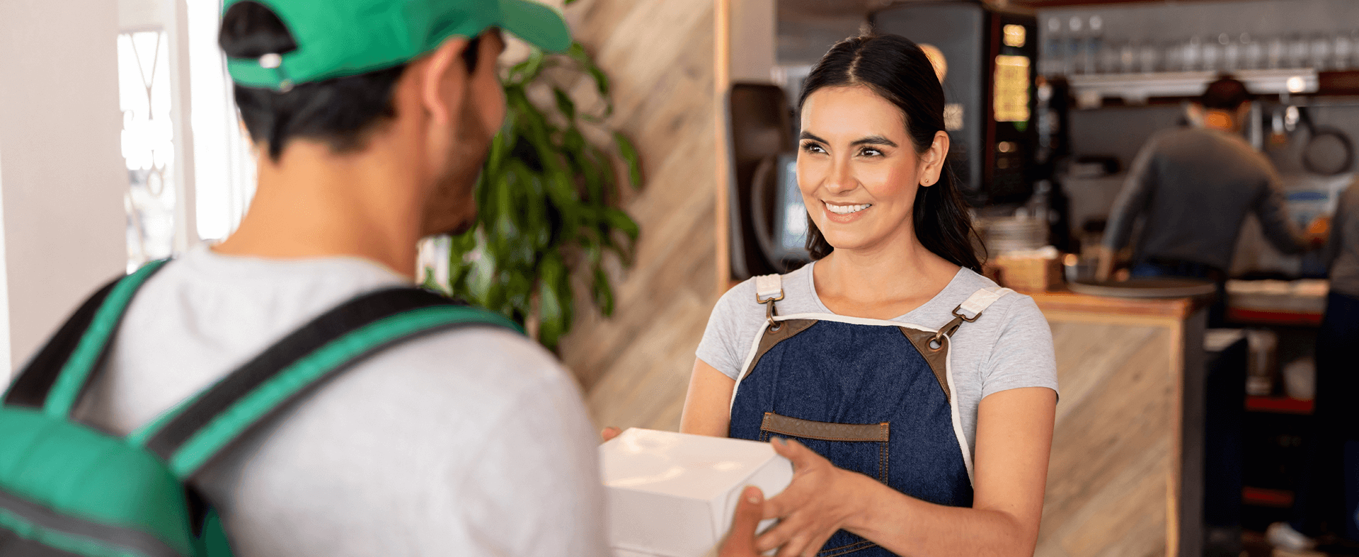 Restaurant server handing delivery person a to-go order.