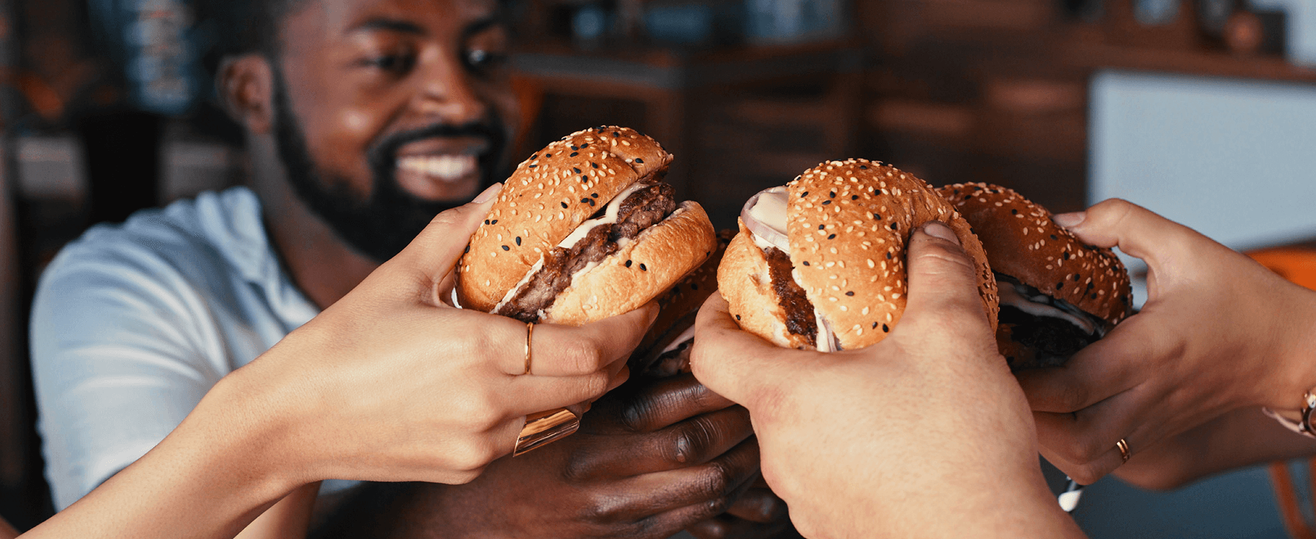 Three ethnically diverse people eating burgers at a restaurant.