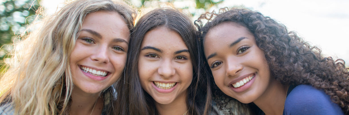 Gen Alpha female friends pose for picture outside.