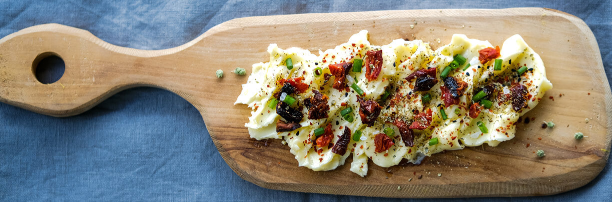Butter board with creamy butter, paprika, green onions and roasted tomatoes.