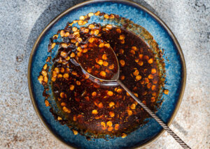Chili crisp in a bowl with red pepper flakes and chili paste.