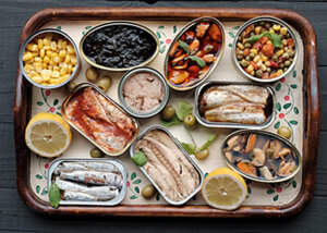 Platter filled with various tinned fish, tinned corn, and tinned mixed vegetables.