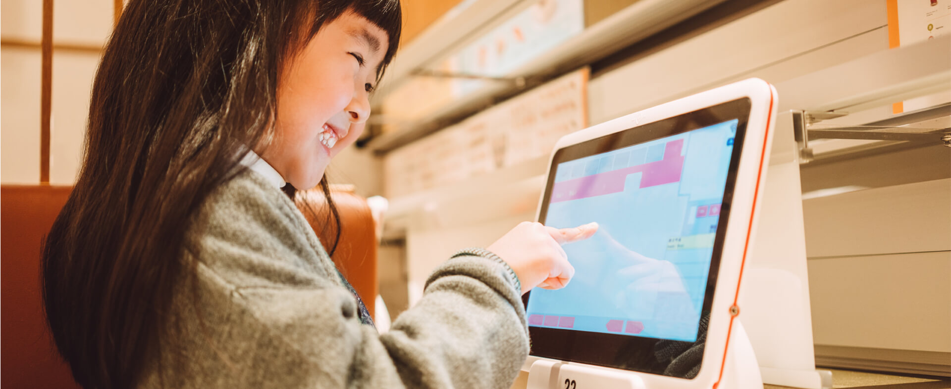 Asian girl using a touch screen to order food at a restaurant.