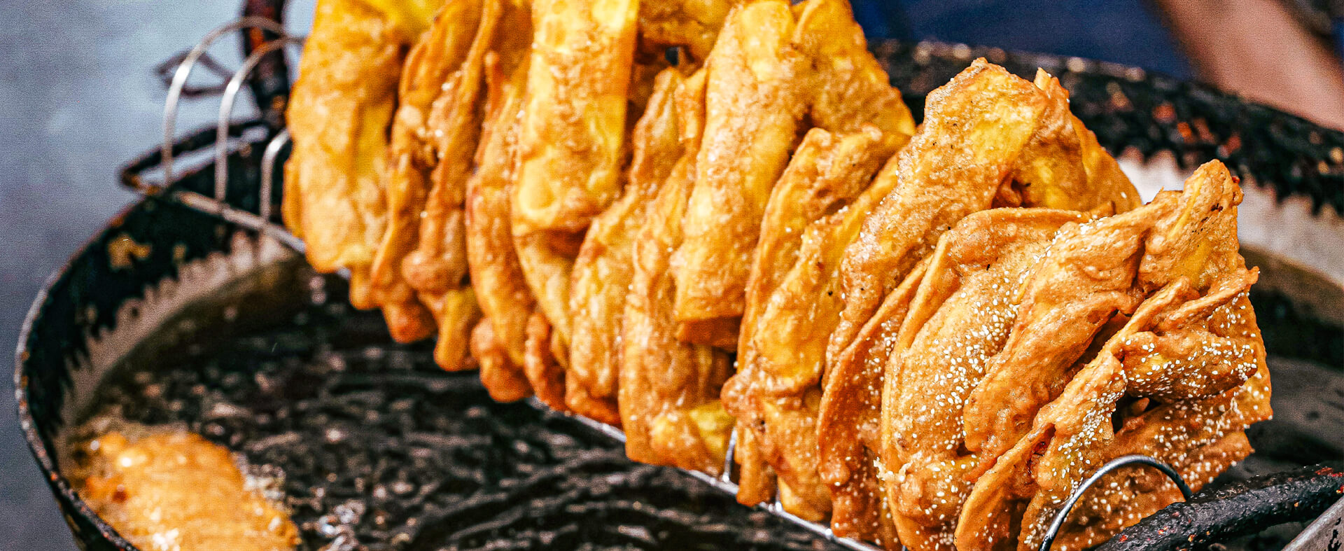 Golden fried Japanese dumplings appetizer skewered across a large hot cast iron pan to catch the oil drippings.