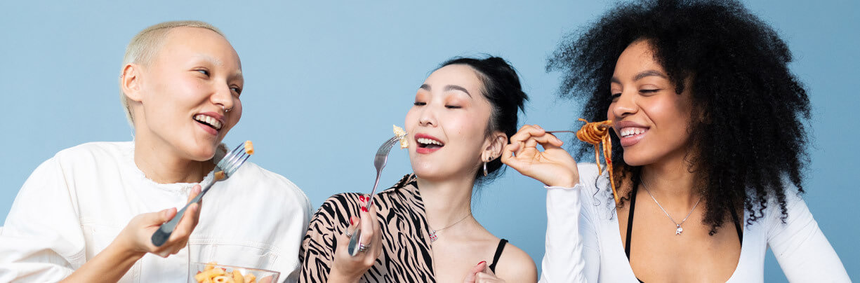 Mixed ethnicity of female Gen Z eating different salads each using a fork.