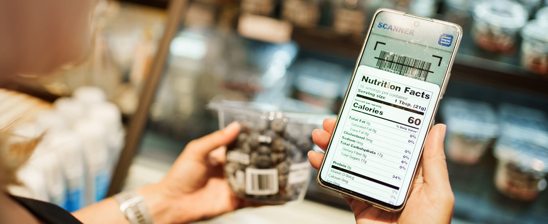 White female holder her smart phone in one hand while holding and a package of chocolate covered cherries in another, scanning the bar code.
