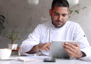 Chef looking at an iPad that shows analytics to help with inventory management and other operational needs.