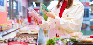 Image of a female consumer checking a QR code on her iPhone for a packaged ham product.