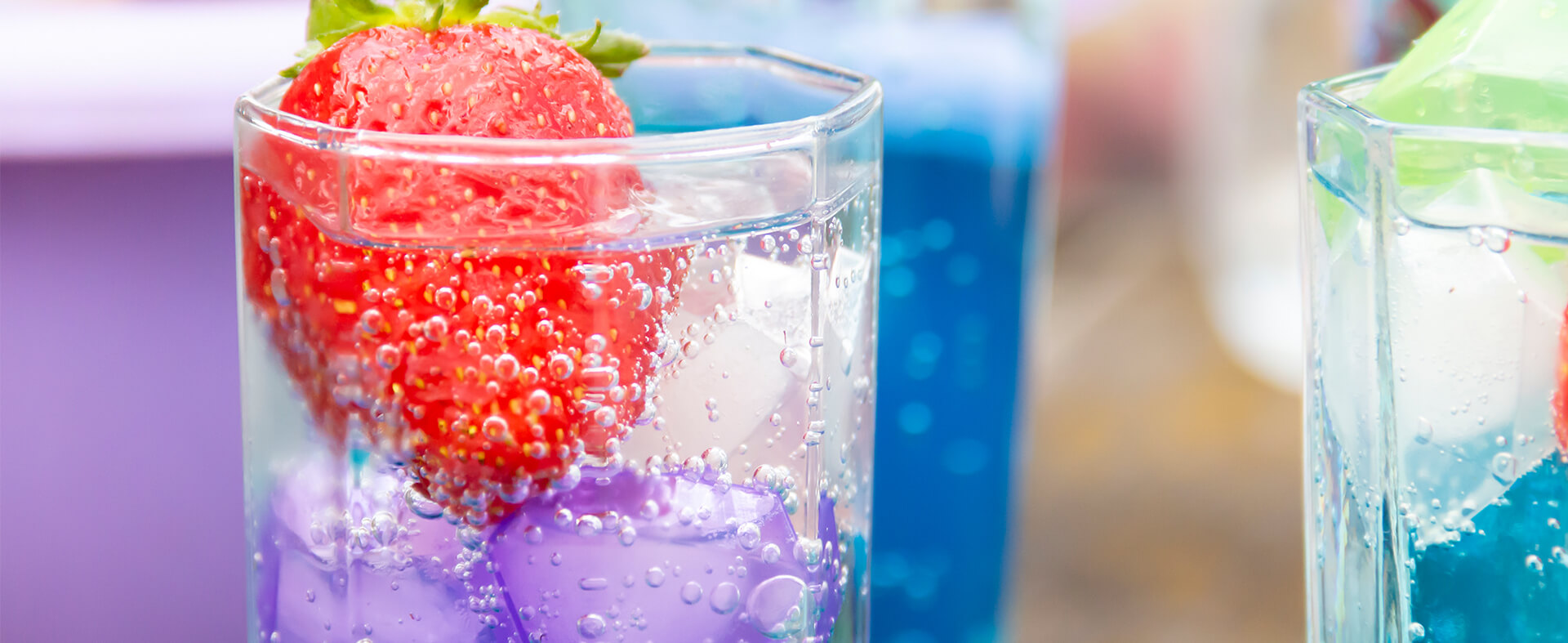 Close-up image of a dirty soda beverage with blue syrup and a large strawberry garnish.