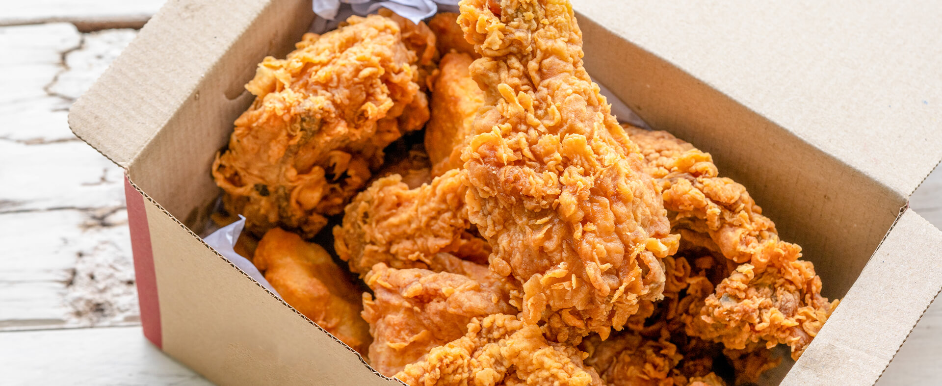 Close-up of a box of fried chicken sitting on a countertop.