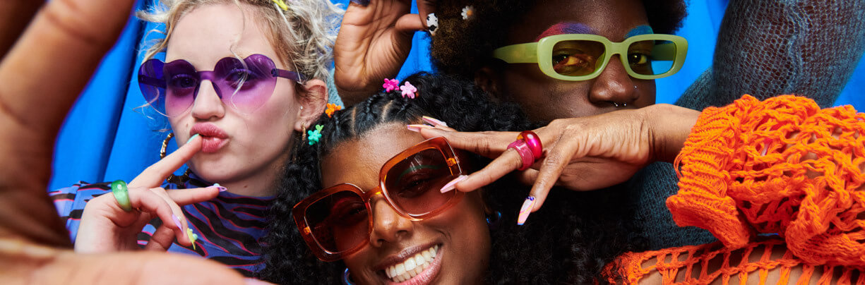 Close-up of three mixed-ethnicity Gen Z friends are wearing sunglasses and having fun.