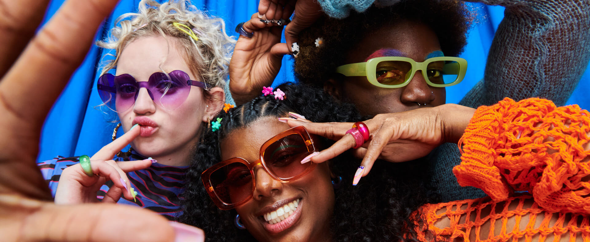 An image of three mixed-ethnicity twenty-something friends wearing sunglasses and having fun.