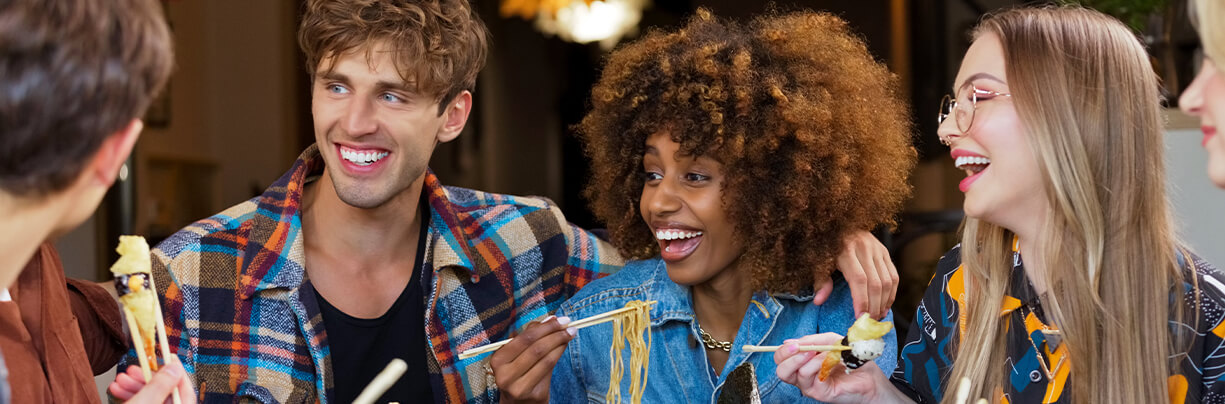 Group of Gen Z friends enjoying a sushi and pasta at a restaurant for lunch.