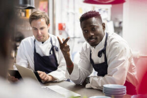 Male chefs discussing at kitchen counter in restaurant